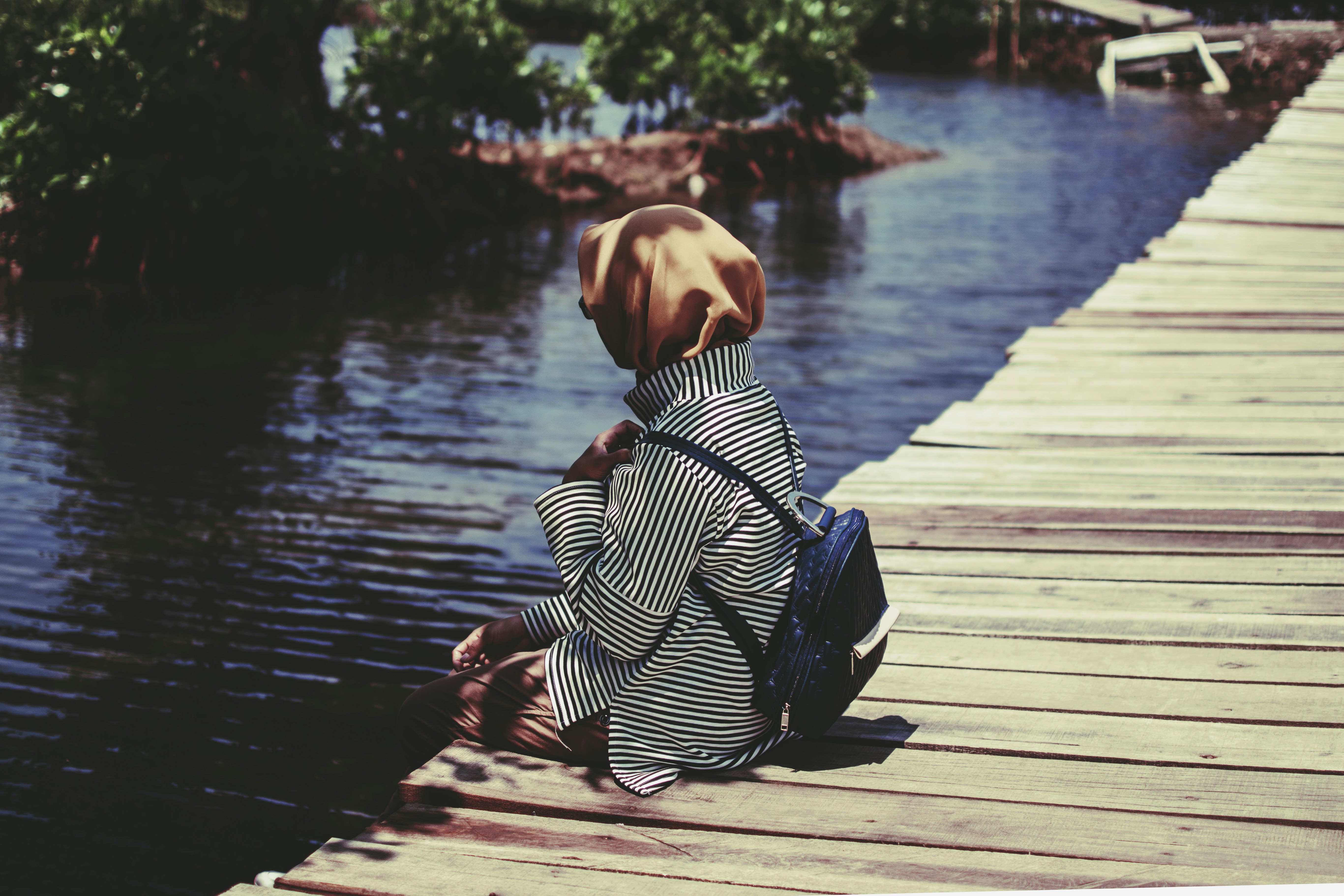 person with backpack sitting on dock