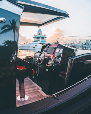 A sleek luxury yacht docked at sunset with calm ocean reflections.
