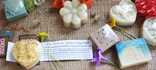 Colorful dried flowers and herbs arranged artistically around soap bars.