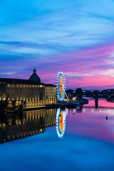 Vue nocturne de Toulouse avec la grande roue illuminée et le Dôme de La Grave, reflet sur la Garonne