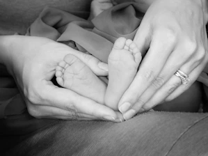 Close-up of a mother’s hands cradling a tiny baby’s feet with tender care.