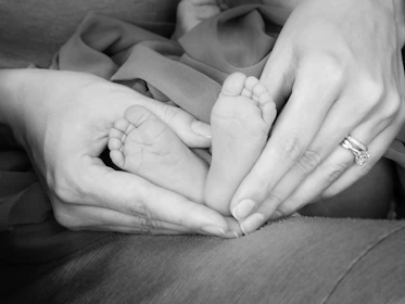 Close-up of a mother’s hands cradling a tiny baby’s feet with tender care.