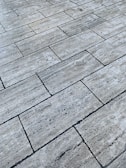A surface covered with rectangular stone tiles arranged in a brick pattern. The texture appears rough and the color is a mix of gray with slight variations giving it a natural stone look.