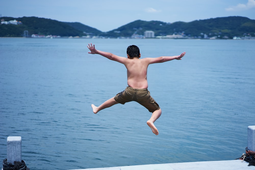 昼間、波止場から水域に飛び込む子供