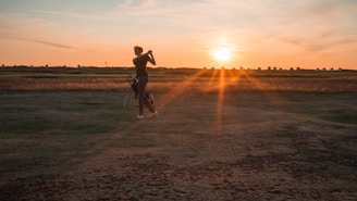 A golfer practicing swing with a training aid on a quiet course at sunset