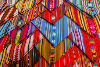 Handwoven huipiles from the Amuzga region displayed with vibrant floral patterns.