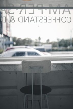 A minimalist urban café scene featuring a person dressed in Lumina’s tailored pants and crisp shirt