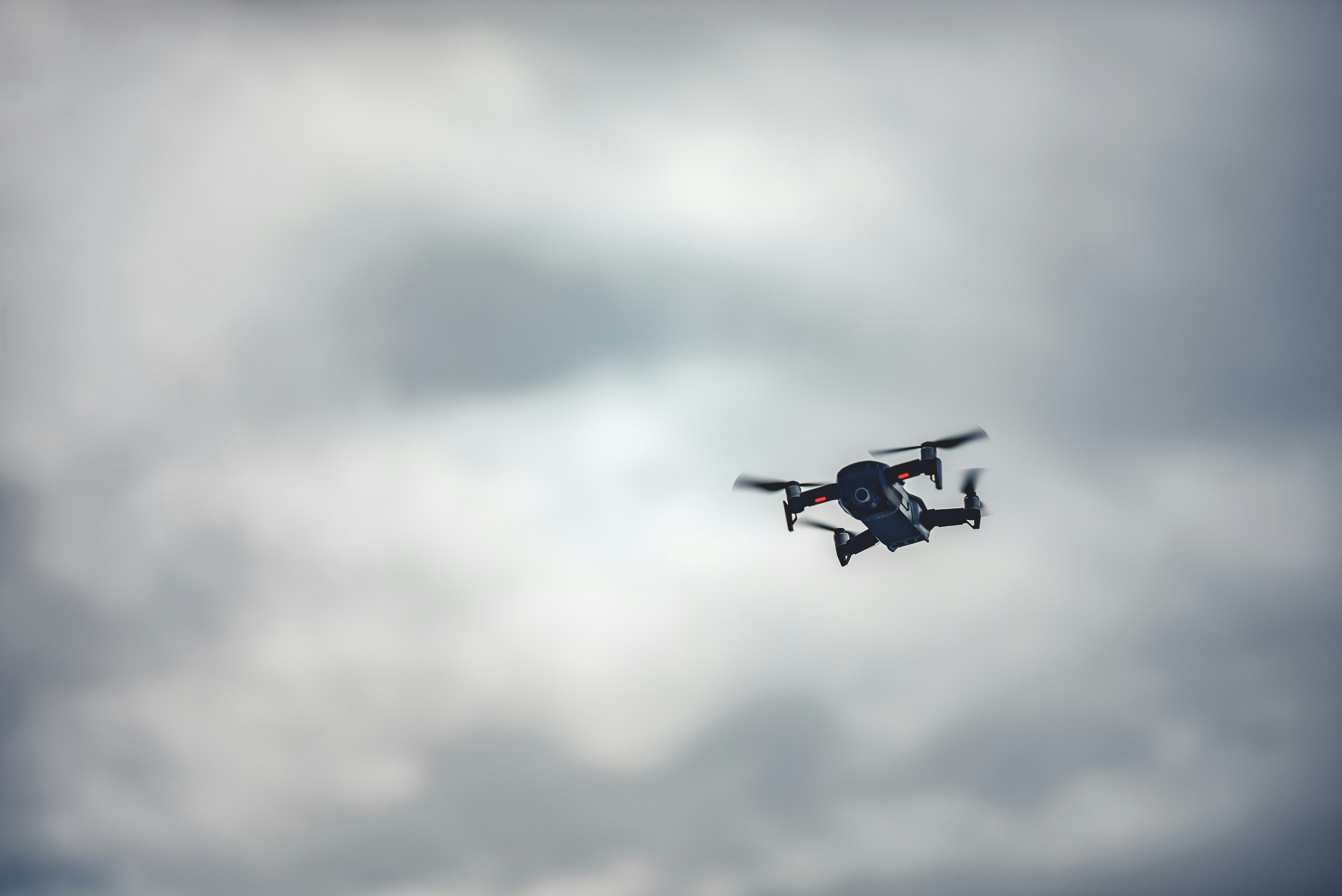 A DJI Mavic Air soars through the air during a cloudy day.