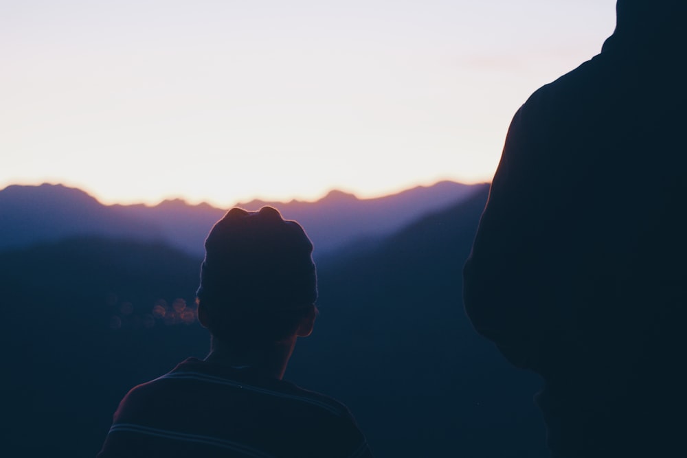 a person standing in front of a mountain at sunset