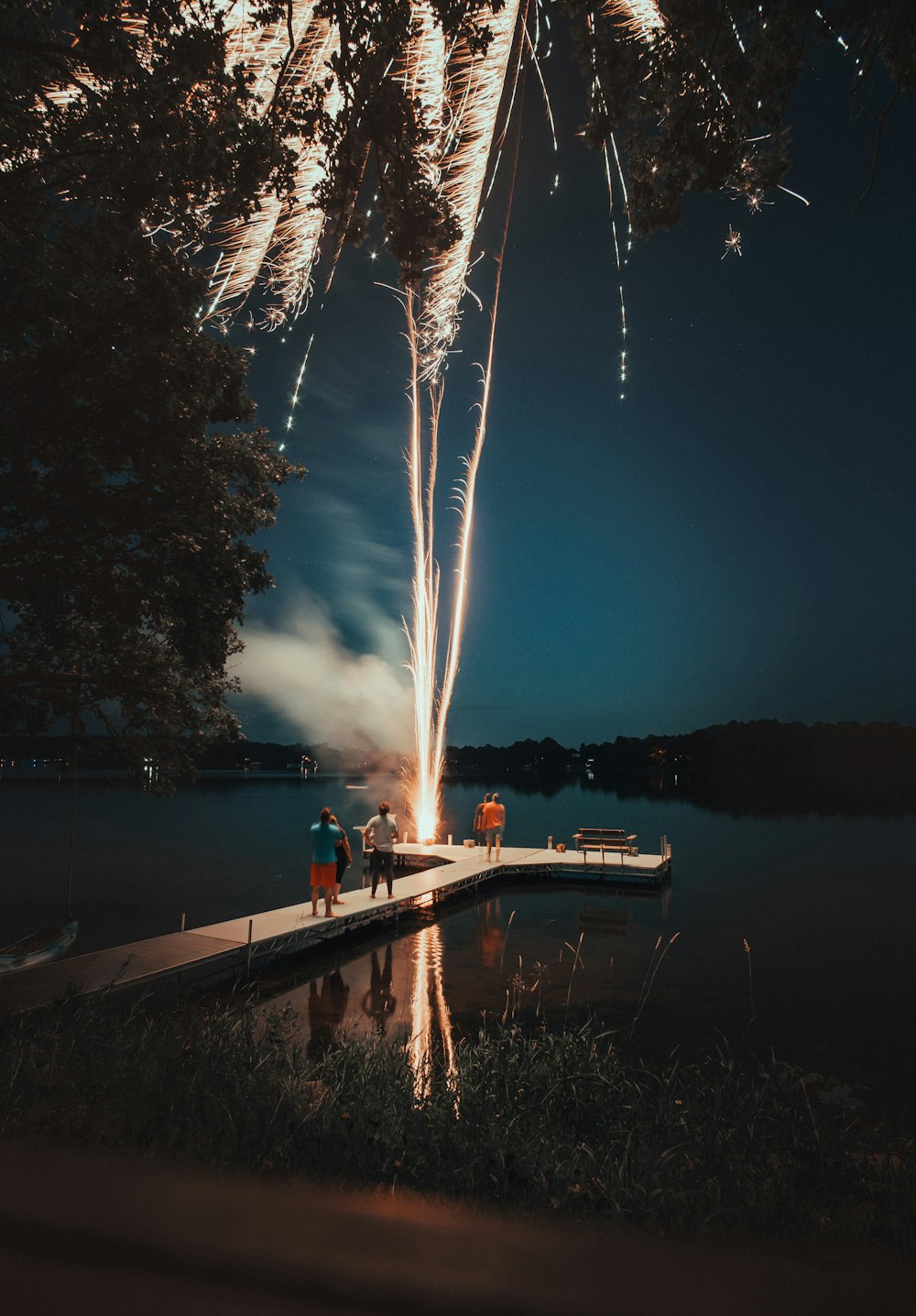 fotografia di uomini in piedi vicino al molo di legno durante la notte