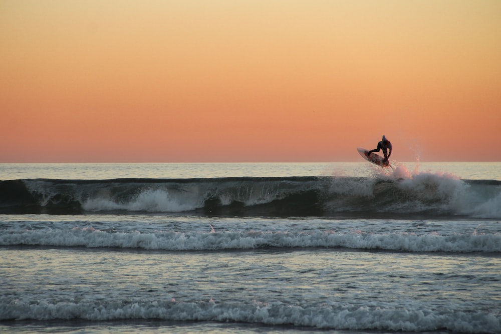 man riding surfboard during sunset