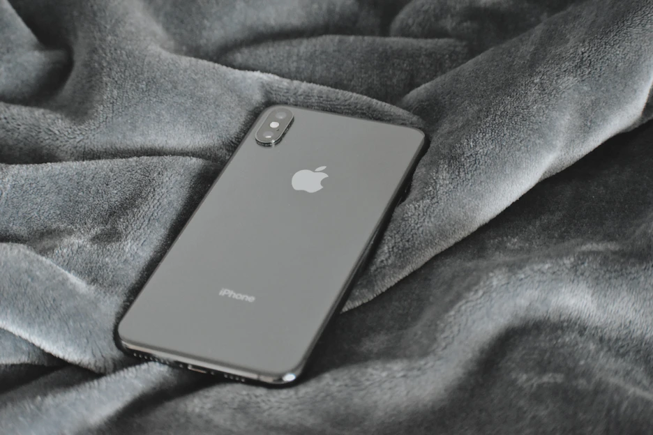 A sleek smartphone resting on a clean white surface with a subtle reflection, highlighting its modern design.