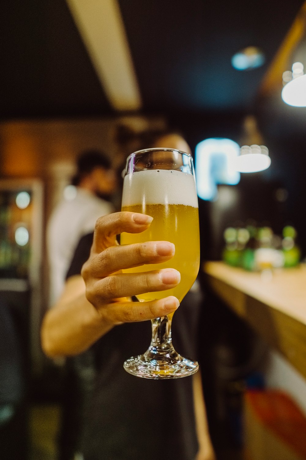 woman holding wine glass with yellow liquid