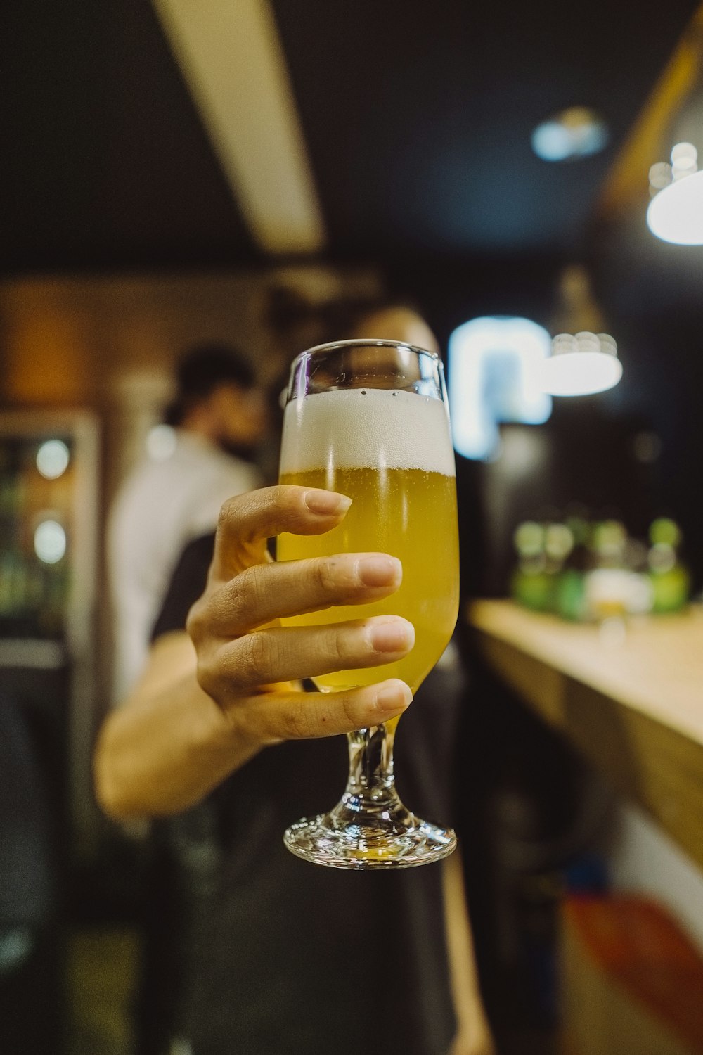 woman holding wine glass with yellow liquid