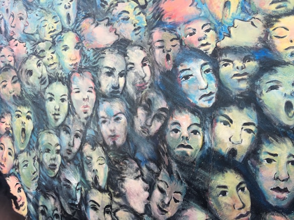 An abstract painting featuring numerous faces with varied expressions, ranging from calm to surprised. The faces are created with soft brushstrokes using a mix of pastel colors. Each face appears to blend into the next, creating a sense of interconnectedness.