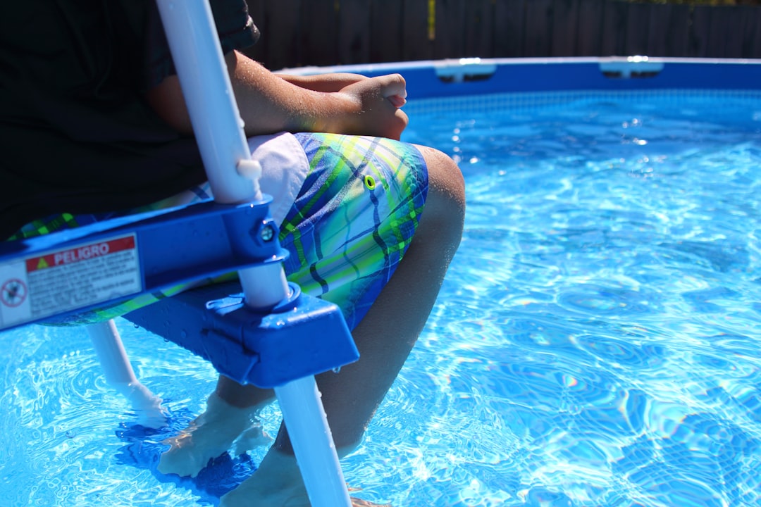 person sitting on pool ladder