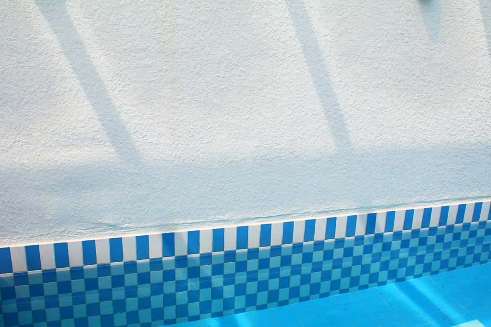 a blue and white tiled swimming pool with a blue bench