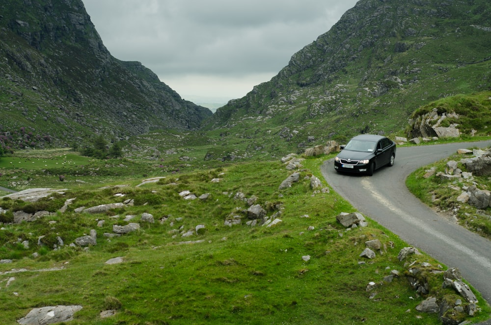 black sedan passing by winding road in the mountain