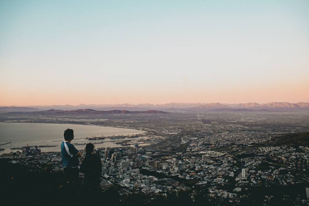 duas pessoas no topo de uma colina com vista para uma cidade