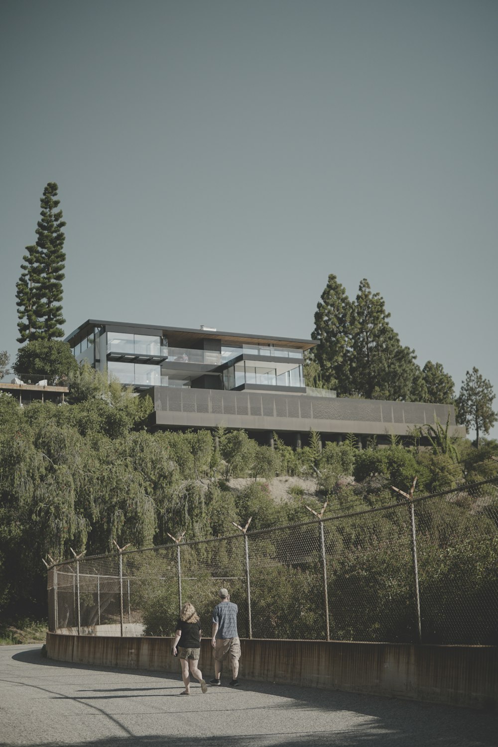 man and woman walking near mesh-link fence