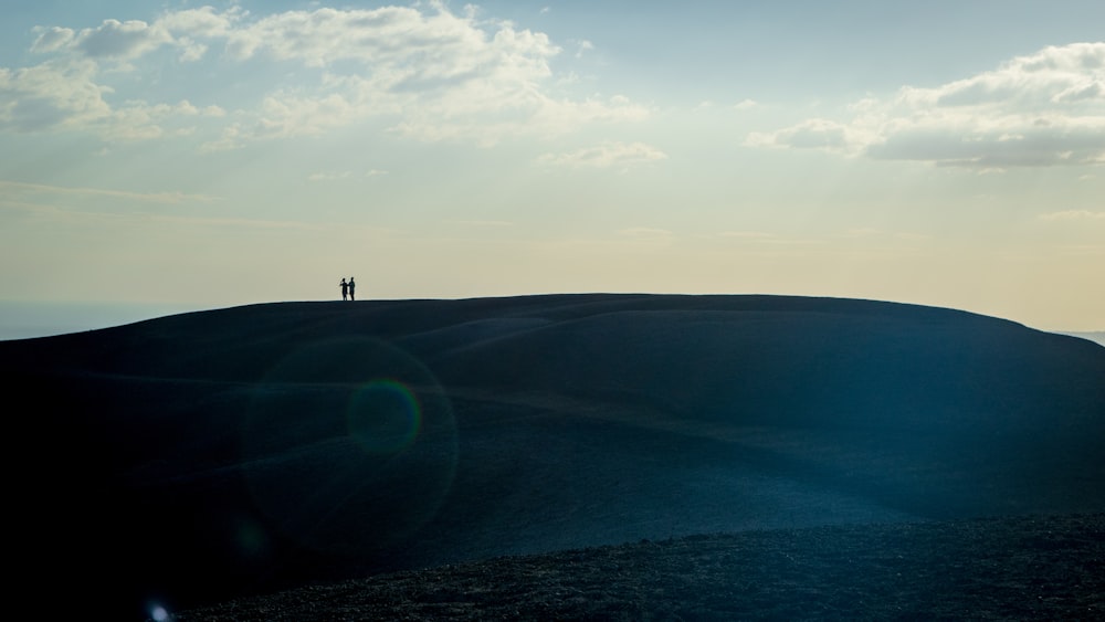 a couple of people standing on top of a hill