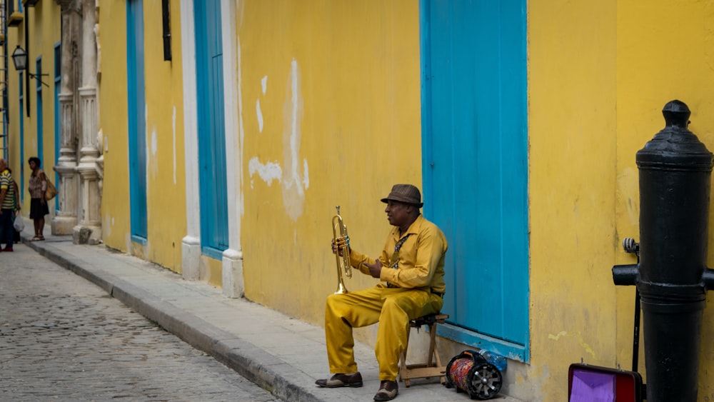 man wearing yellow suit sitting beside wall