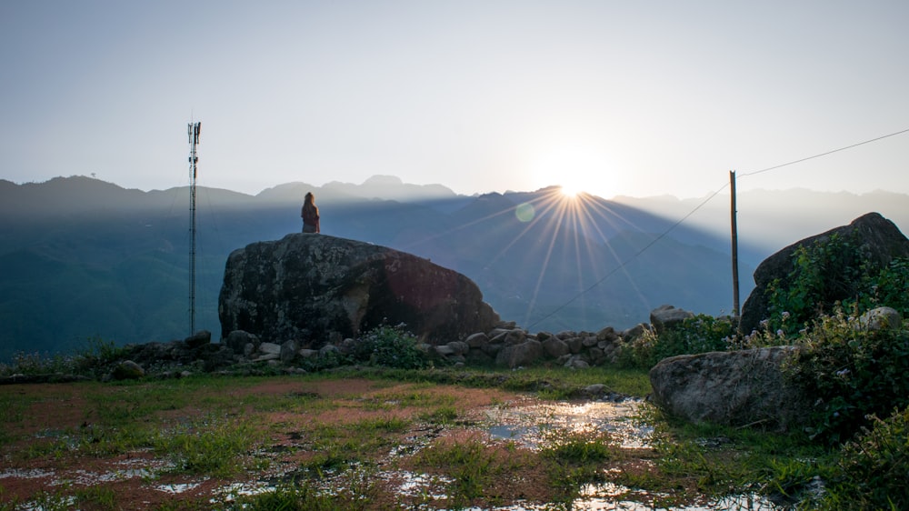 person sitting on rock near mountain at daytime