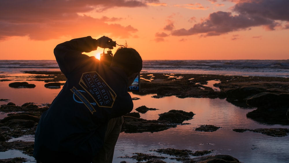 夕暮れ時に海辺に立つ男