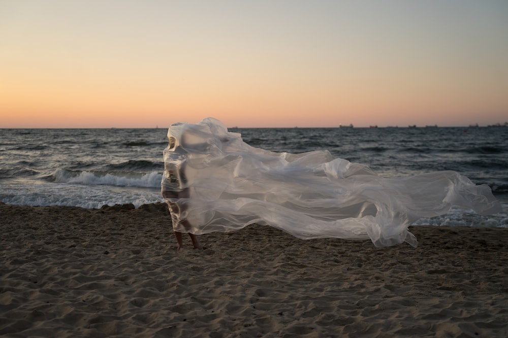 a woman standing on top of a sandy beach next to the ocean