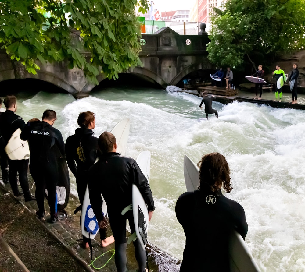 Grupo de pessoas segurando pranchas de surf no rio