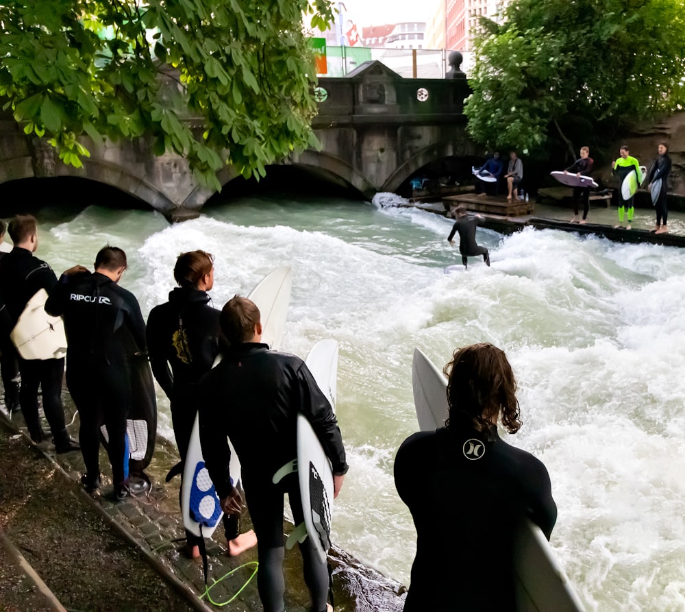 group of people holding surfboards at the river