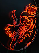 A glowing neon sign in vivid red, depicting an abstract, swirling design against a dark background. The intricate curves and lines create a dynamic, artistic shape that seems both fiery and bold.