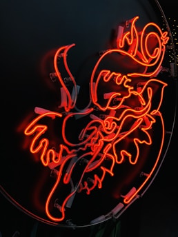 A vibrant splash of bold, colorful abstract art swirling around a glowing Greek script.