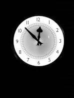 a white clock with black numbers on a black background