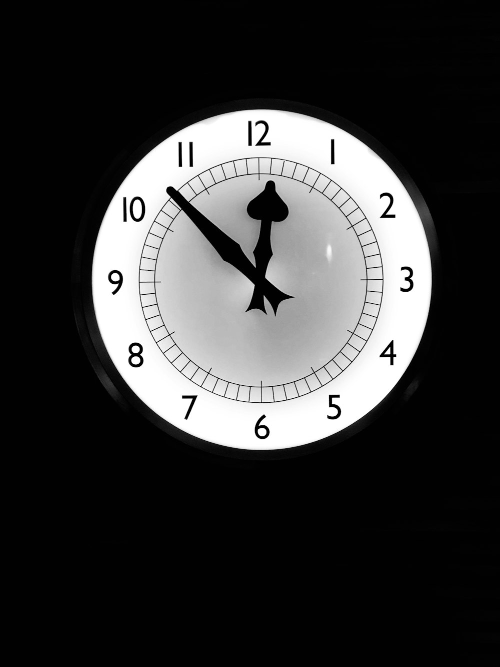 eine weiße Uhr mit schwarzen Zahlen auf schwarzem Hintergrund