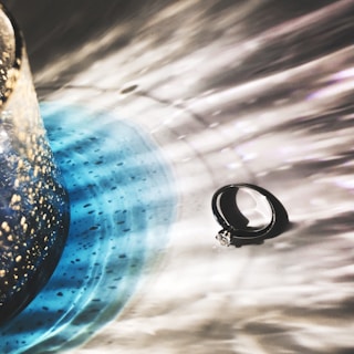 An artistic shot of a wedding ring on a decorative surface.
