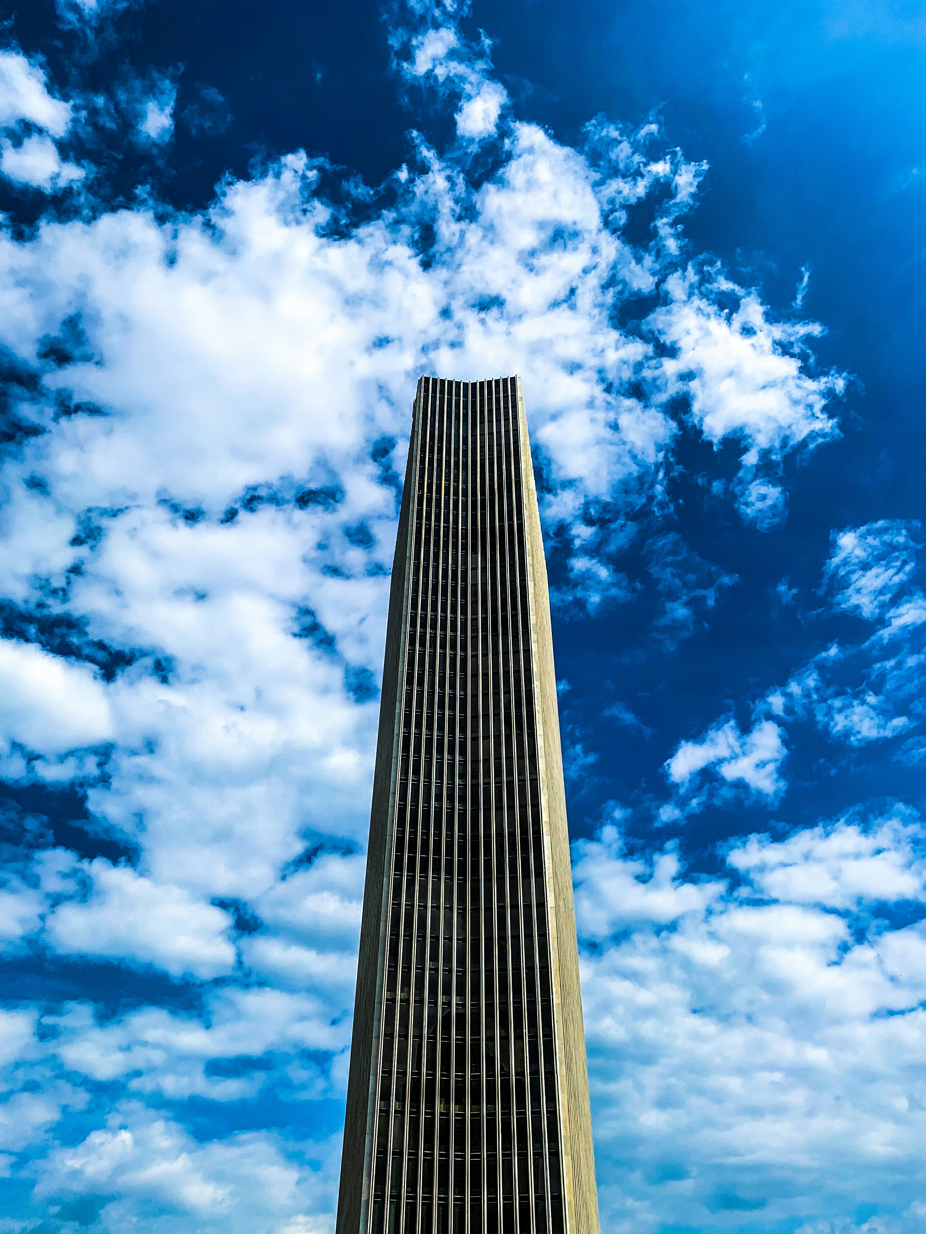 edificio blanco de gran altura bajo cielos nublados blancos y azules