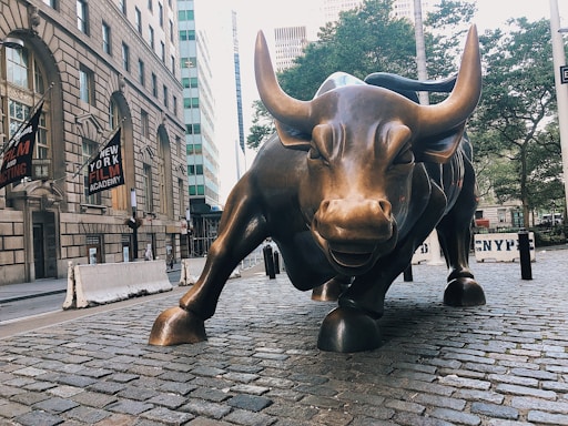 The iconic bronze bull statue at Amsterdam Beursplein under a clear sky, symbolizing financial strength.