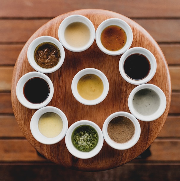 a wooden table topped with white cups filled with sauces