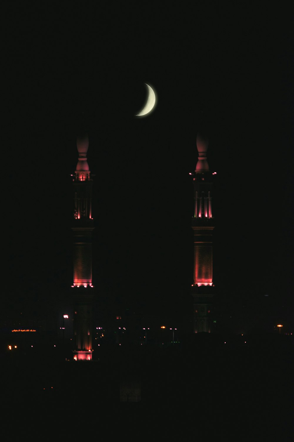 crescent moon above buildings lighted at night