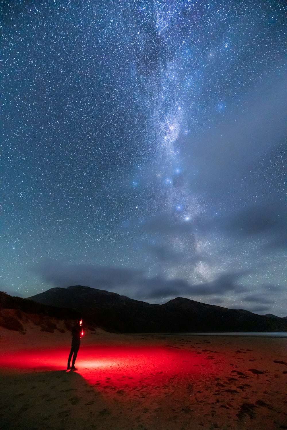 silhouette of person holding light under starry sky