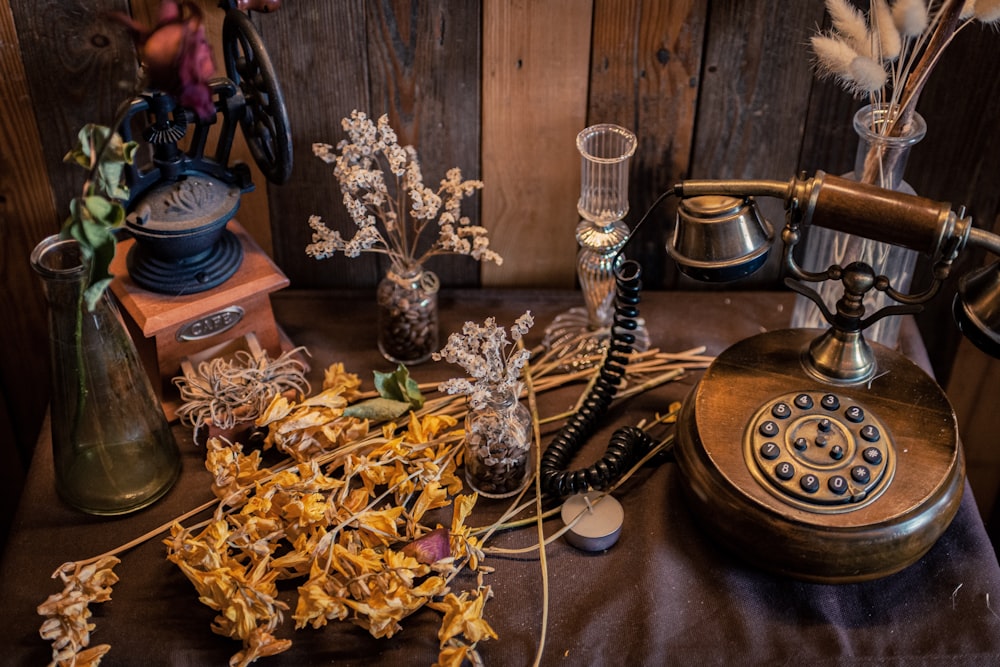 brown and gray rotary phone beside yellow flowers