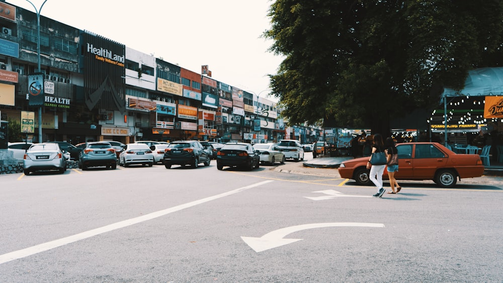 woman walking beside red sedan