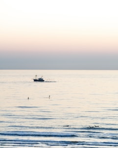 A serene ocean shore at sunrise with a small group preparing for a peaceful paddleboarding session.