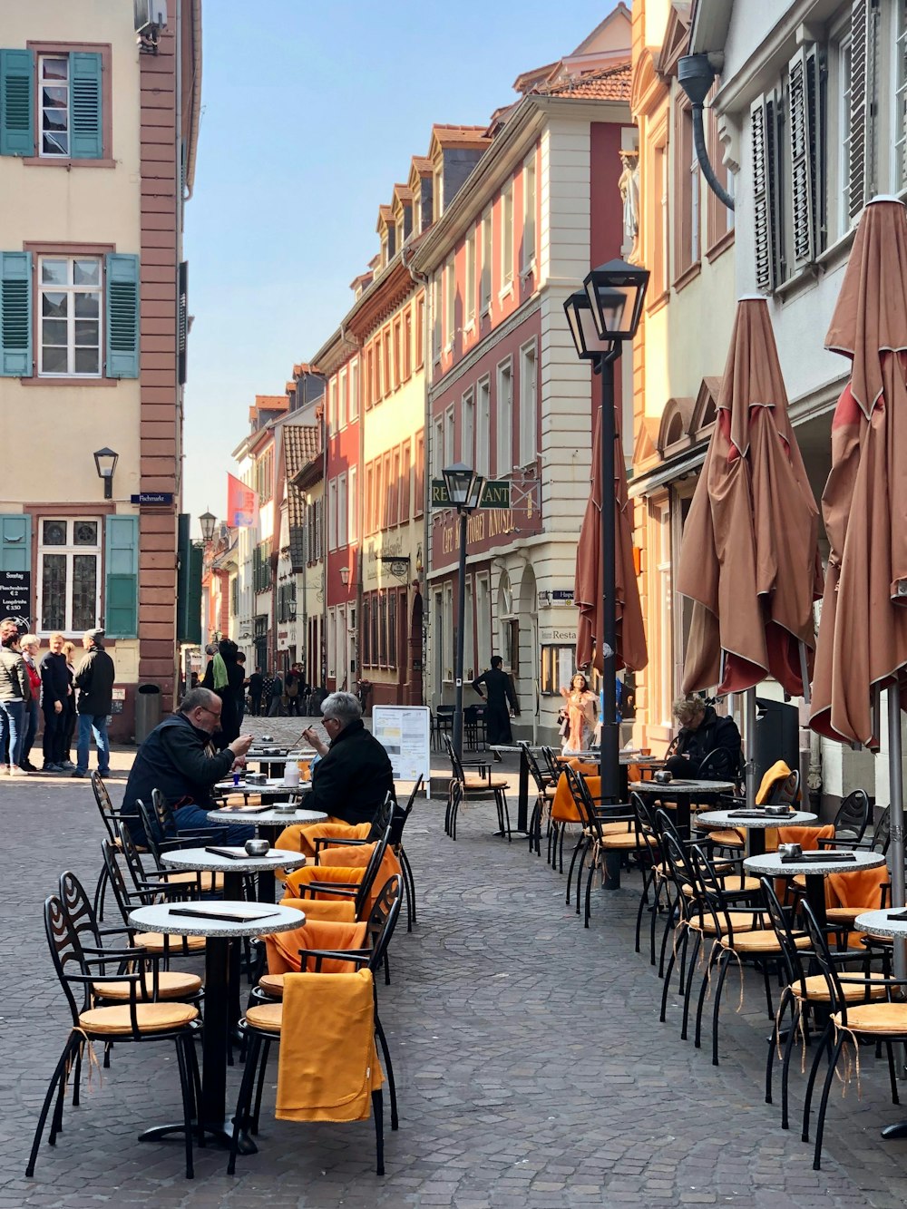 few people sitting near dining table viewing people standing near buildings