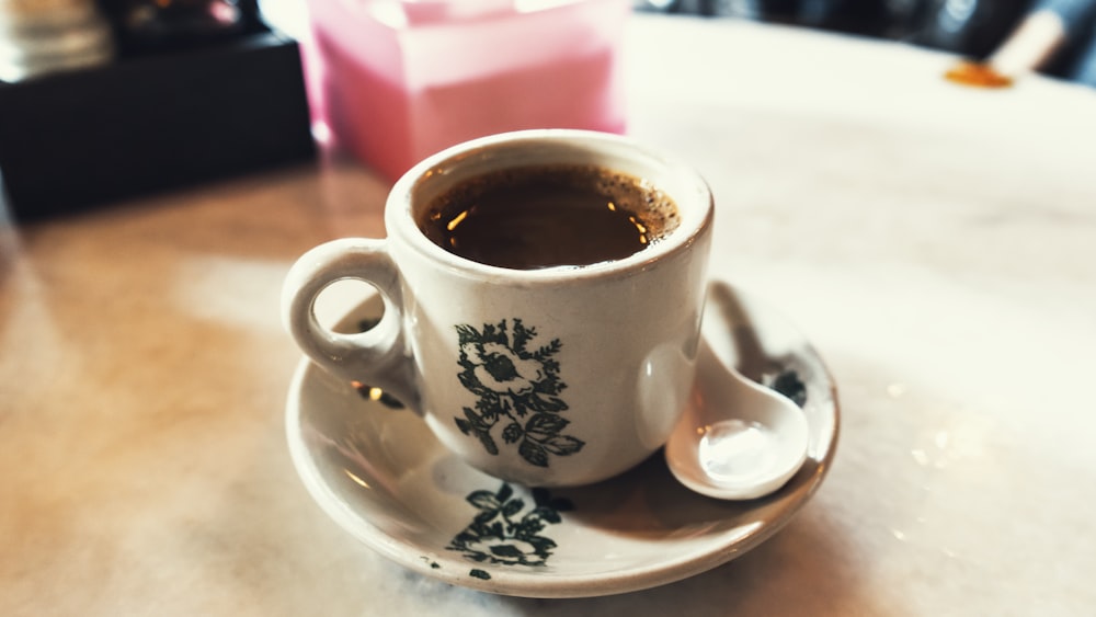 white and blue floral ceramic mug with coffee