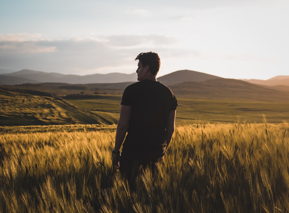 man wearing black shirt standing on brown field