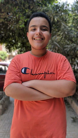 A cheerful person wearing a bright personalized t-shirt standing confidently outdoors.