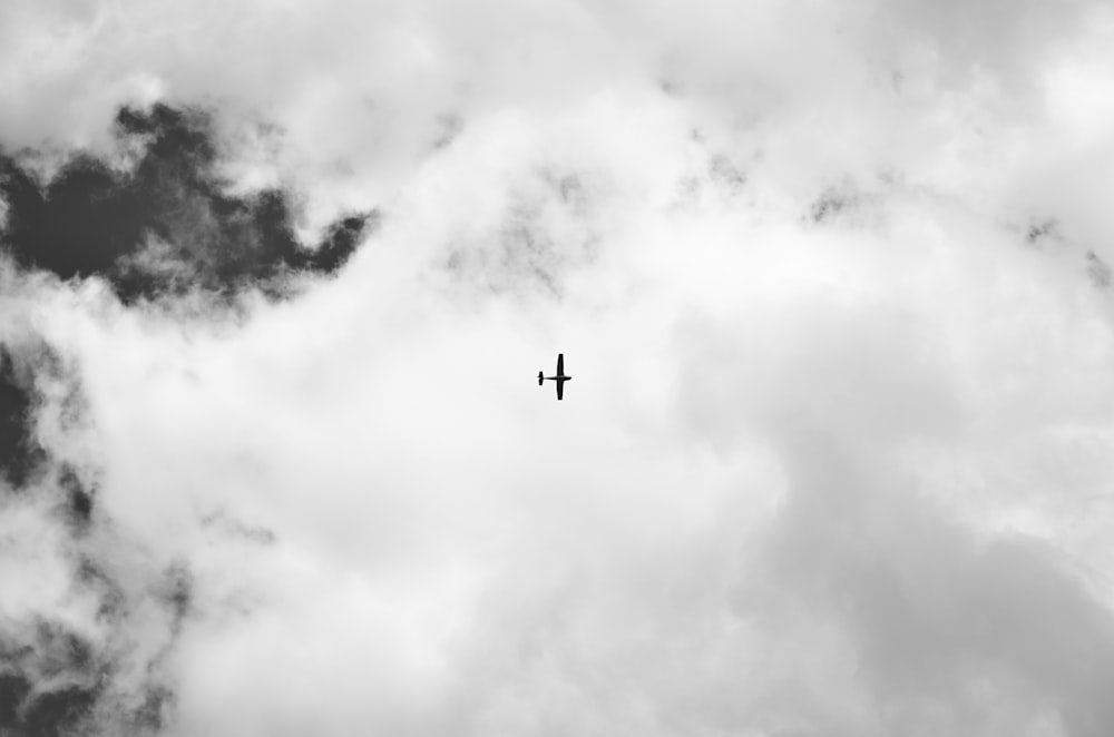 silhouette of airplane under white clouds