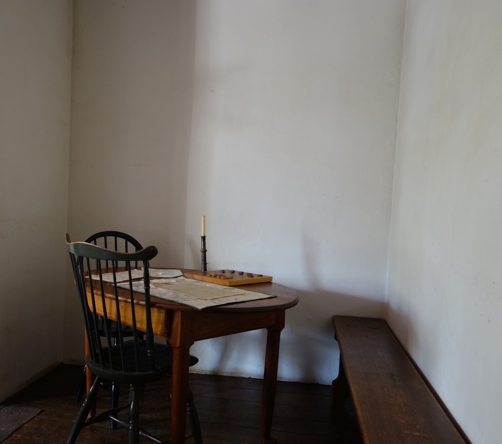 round brown wooden table and two black windsor chairs